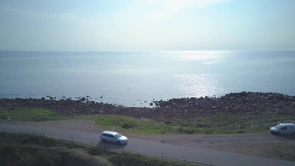 Drone shot of a car driving along the sea in sweden