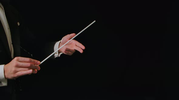 Moving Hands of an Orchestra Conductor Directing Musicians with Movement of Baton on Black