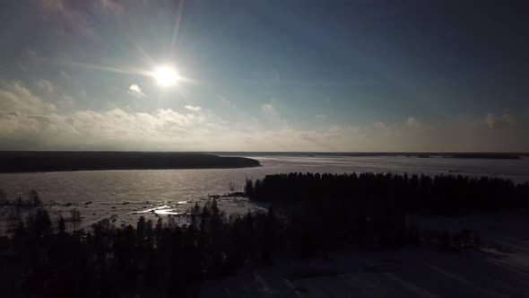 Aerial view of nature at rest. Snowy winter landscape with trees casting long shadows on the ice. Be