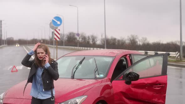 Scared Girl Talking on the Phone After a Car Accident in the Rain, Car Is Broken