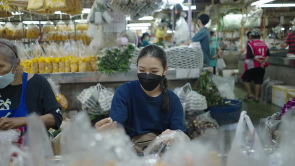 A Senior And Young Flower Seller Making Aesthetic Thai Garlands Within Bangkok Central Flower Market