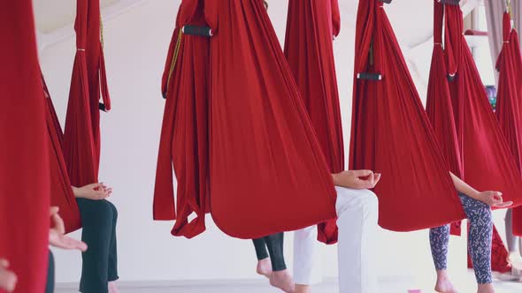 Women Sit in Hammocks with Fingers in Mudra Position