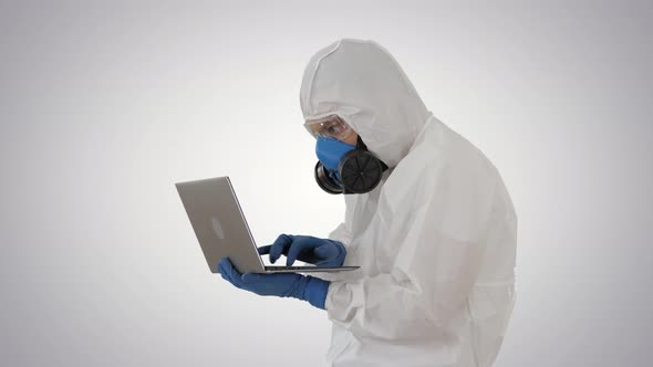 Doctor in Protective Suit Working on Laptop and Having Good Results on Gradient Background