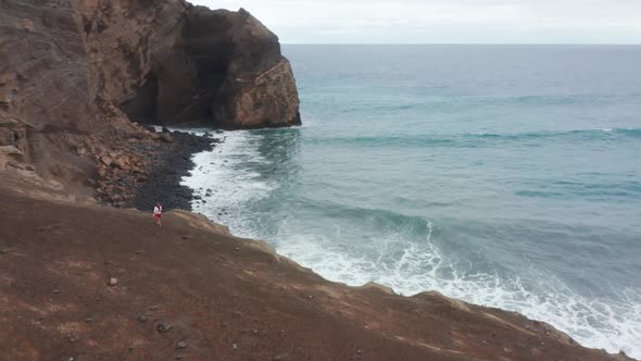 Man Walking on Rocky Coast at Capelinhos Volcano Faial Island Azores Portugal