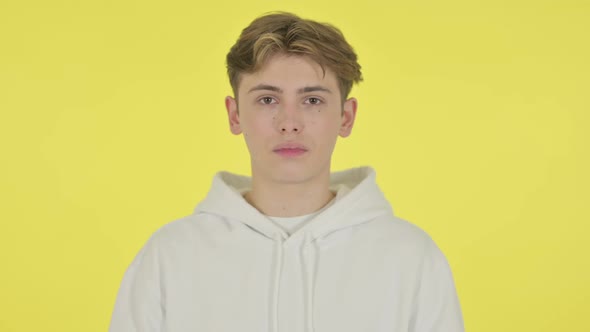 Serious Young Man Looking at the Camera on Yellow Background