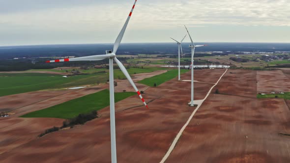 Aerial view of white wind turbines on brown field in cloudy day