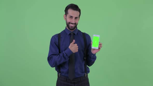 Happy Young Bearded Persian Businessman Showing Phone and Giving Thumbs Up