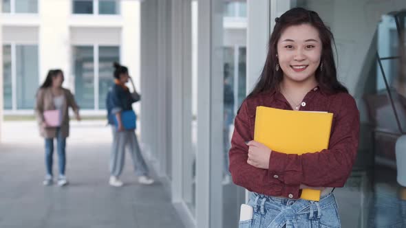Female university student holding folders and looking at the camera