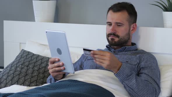 Online Shopping on Tablet by Tired Man in Bed