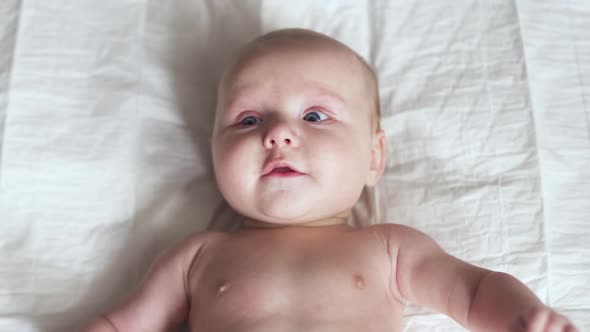 Toddler on Bed, Moves His Hands, Smiles and Tries To Talk