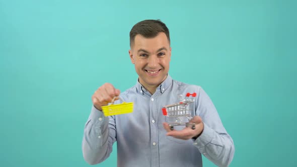 A Customer Man in a Blue Shirt Happily Demonstrates a Toy Basket and Shopping Cart in His Hands