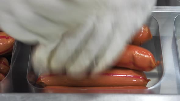 Hands of Operator Stacking Finished Sausages in the Package