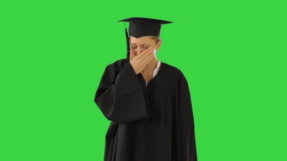 Young Graduate Girl Student in Mantle Coughing on a Green Screen, Chroma Key