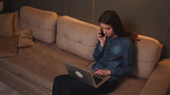 Focused Businesswoman Talking on a Mobile Phone While Working on a Laptop