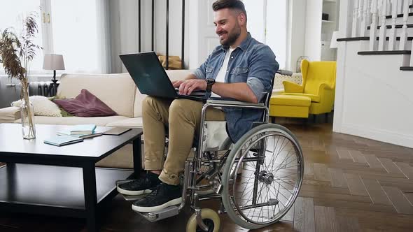 Bearded Man in Wheelchair Remotely Working on Personal Computer at Home