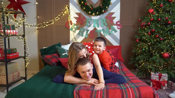 Beautiful Happy Family in Pajamas in the New Year's Bed