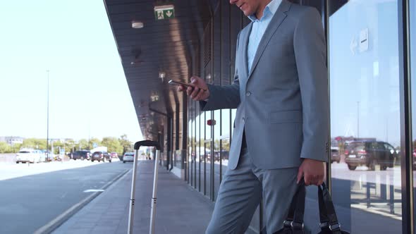 Elegant businessman using smartphone in airport. Young mail entrepreneur.