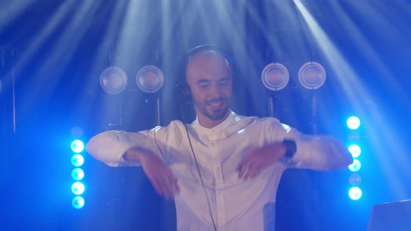 Live DJ Performance of Energetic Bald Man with Headphones Dancing on Party Concert Musician Stage