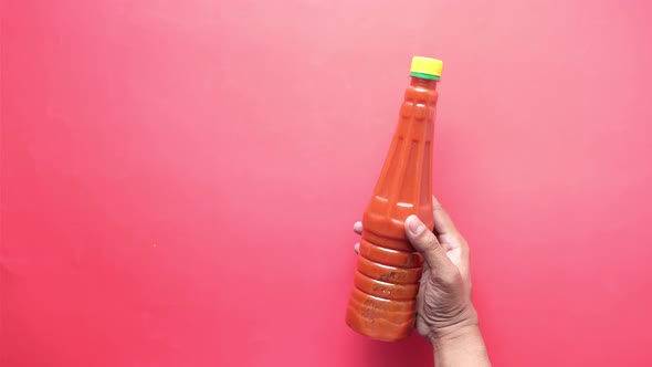 Holding Tomato Sauce in a Bottle on Red Background