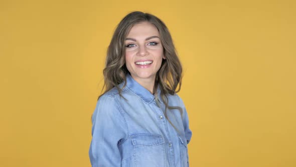 Young Girl Turning Around And Smiling Isolated on Yellow Background