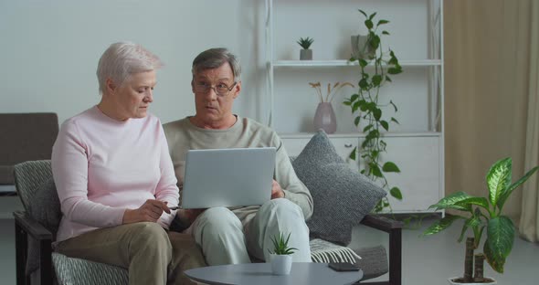 Focused Old Retired Couple Mature Family Talking Using Modern Laptop Doing Internet Shopping Choose