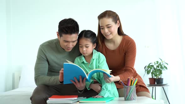 Asian Father and Mother Reading Book with Daughter