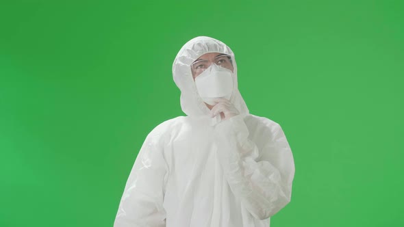 Asian Man Wear Protective Uniform PPE And Thinking About Something In The Green Screen Studio