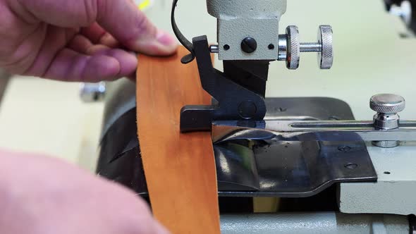 Man Using a Machine To Frame the Edge of a Leather Piece of Material. Close Up View. Craft and