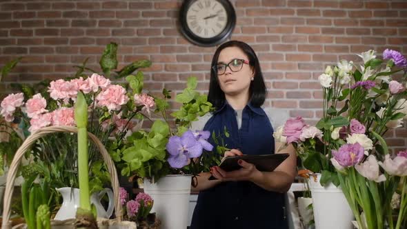 florist in a flower shop with a digital tablet checks and counts flowers.