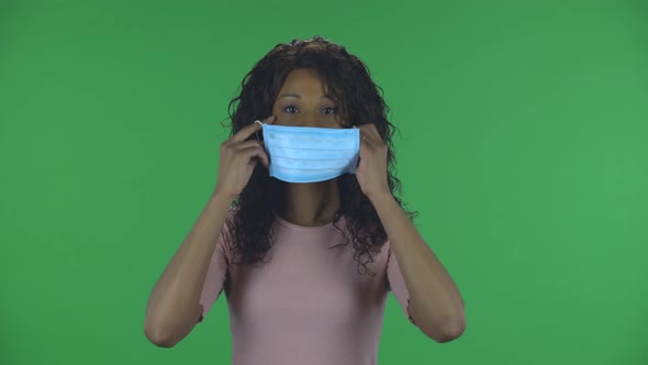 Portrait of Beautiful African American Young Woman Puts on Medical Mask. Burning Brunette with Wavy