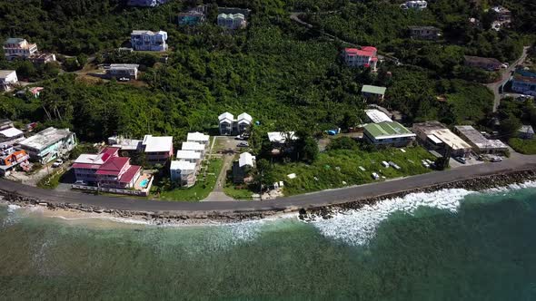 Aerial approach over water to local homes on a beach BVI island Tortola.