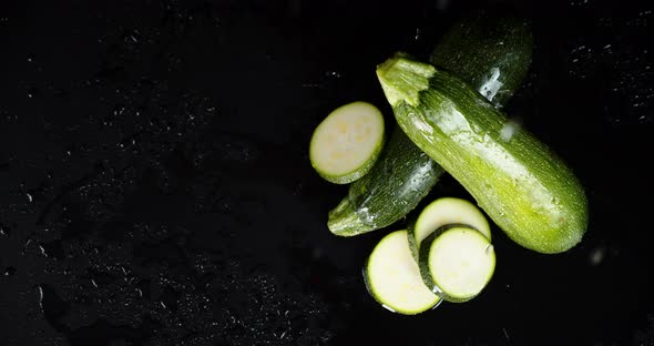 Whole and Pieces of Fresh Zucchini Falling Water Drops. 