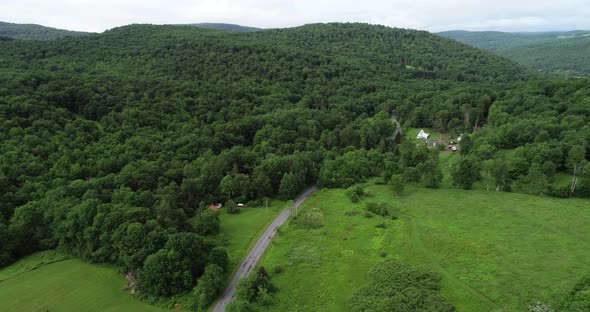 A car drives on a road into the beautiful scenery of the Catskill Mountains in New York.