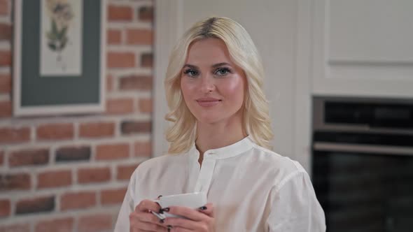 Portrait of Satisfied Woman Drinking Tea on Kitchen