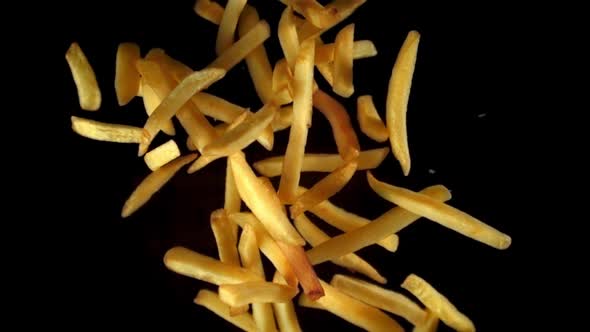 Super Slow Motion French Fries Flying in the Air Against a Black Background