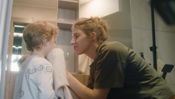 Mother Wiping Kid Face with Towel in Bathroom