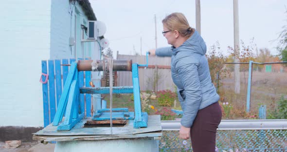 Curvy Woman Gets Water From Old Drawwell in Village Yard