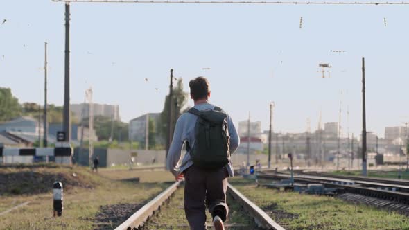 Happy Man Runs Along Train Tracks and Smiles Raising His Hands Up