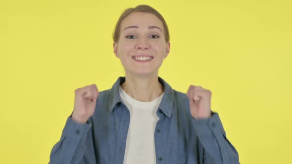 Successful Young Woman Celebrating on Yellow Background