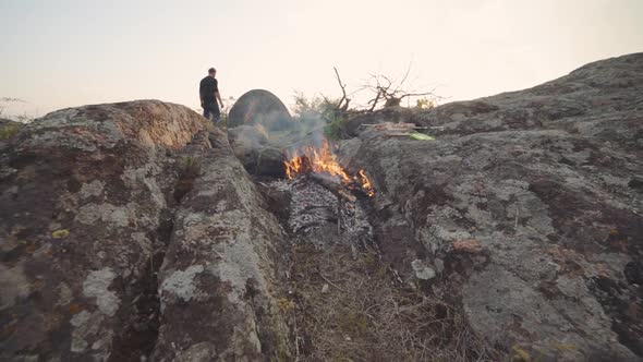 the Traveler Guy Cooks a Chicken on Fire Near His Tent in the Mountains