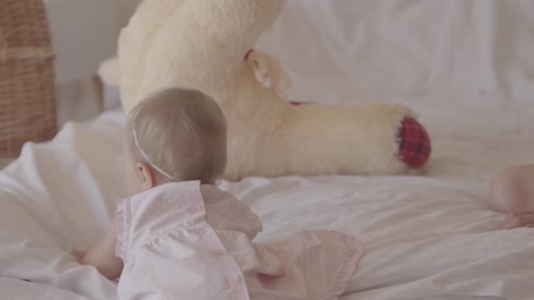 Little Baby Girl Playing on the Bed Indoors. Cute Child at Home. Beautiful Child with Mother. Having