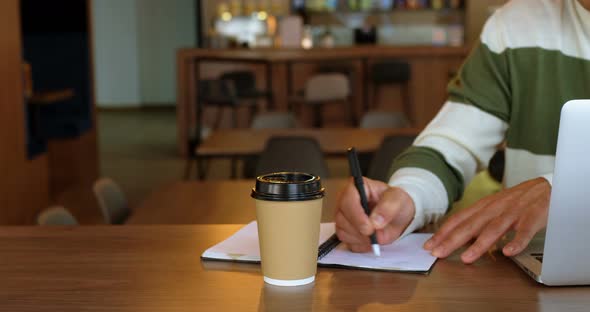 Male executive writing on diary in office cafeteria