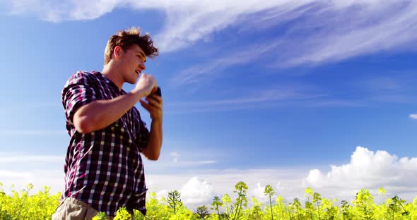 Man taking picture from camera in mustard field