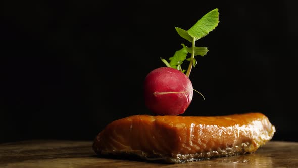 Delicious radishes lies on pieces of smoked salmon on black background