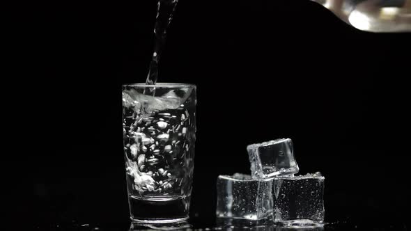 Pouring Up Shot of Vodka Into Glass. Black Background. Pour of Alcohol Drink