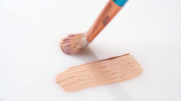 Beige Smear of Makeup Foundation Cream with a Brush on White Background