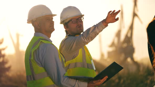 Male Engineers in Hardhats Are Discussing a Project