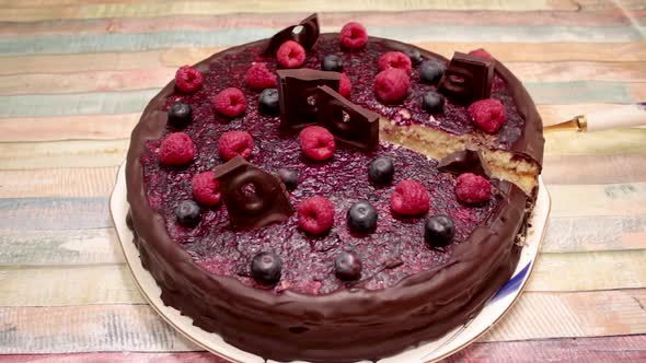 Taking a slice of chocolate and berry pie. Eating cake with strawberries and blueberries. Delicious