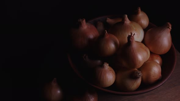 Pile of Whole Bulbs of Raw Onion in Ceramic Bowl on Table