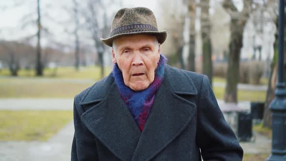 Senior old man walks, coughing outdoors. Retired elderly people care concept	